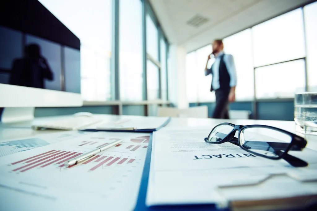 Reporte financiero y documentos empresariales sobre una mesa de trabajo en una oficina corporativa para planificación de flujo de caja.