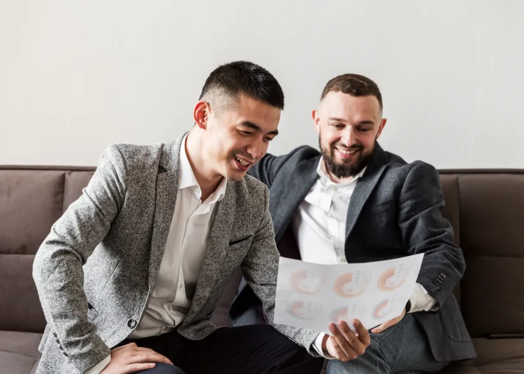 Dos empresarios revisando documentos y analizando estrategias para obtener más referencias y recomendaciones de clientes.