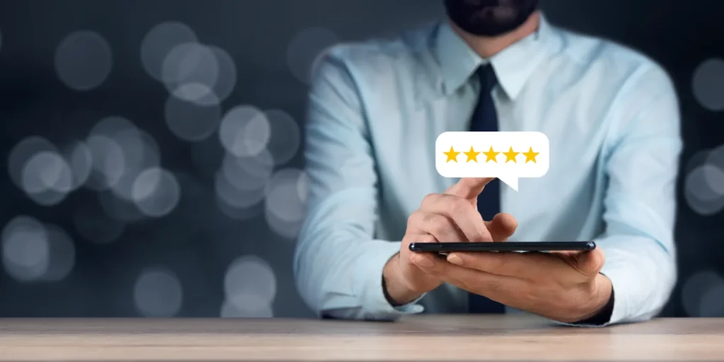 Persona utilizando un smartphone para dejar una reseña positiva con estrellas y mejorar la reputación online de un negocio.